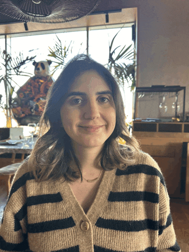 a woman wearing a striped sweater is smiling in front of a window