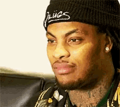 a man with a beard and tattoos is wearing a black beanie and earrings .