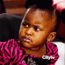 a little girl is making a funny face while wearing a pink zebra print dress .