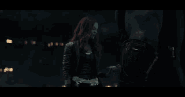 a blurred image of a woman with red hair standing in a dark room .