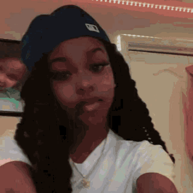 a young girl is taking a selfie in front of a mirror while wearing a hat .