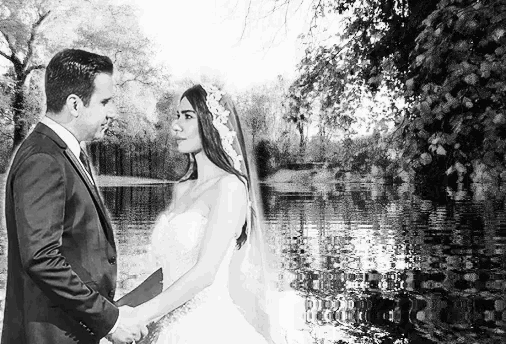 a bride and groom are holding hands in front of a lake