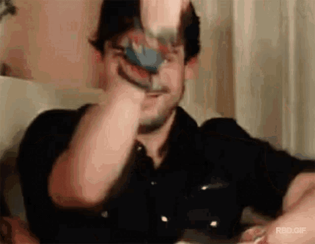 a man sitting on a couch playing a video game with a gif that says rbd.gif at the bottom