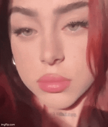 a close up of a woman 's face with red hair and pink lipstick .