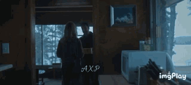 a man and a woman are standing in a room with the word axp on the bottom left