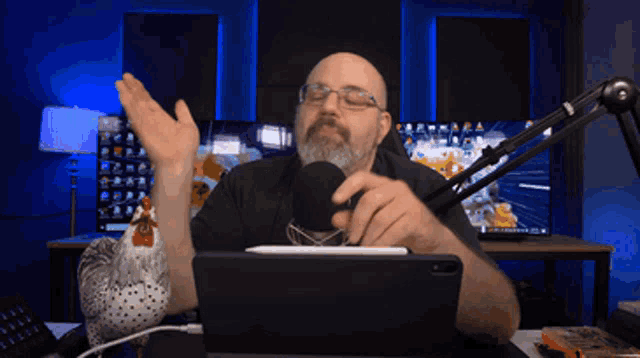 a man with a beard is sitting at a desk with a microphone and a tablet