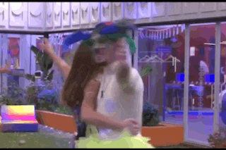 a man and a woman are hugging each other in a room while wearing colorful hats .