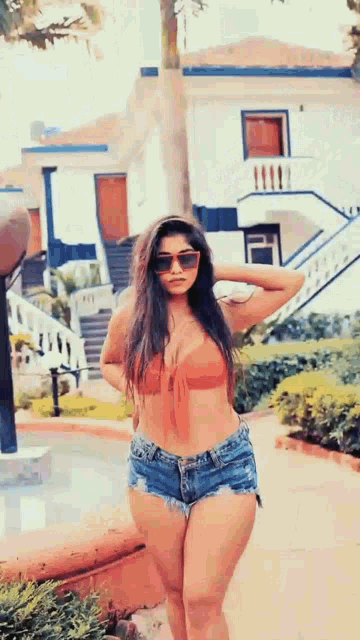 a woman in a bikini top and shorts is walking down a path .