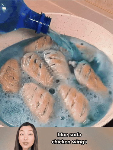 chicken wings are being cooked in a pan with blue soda