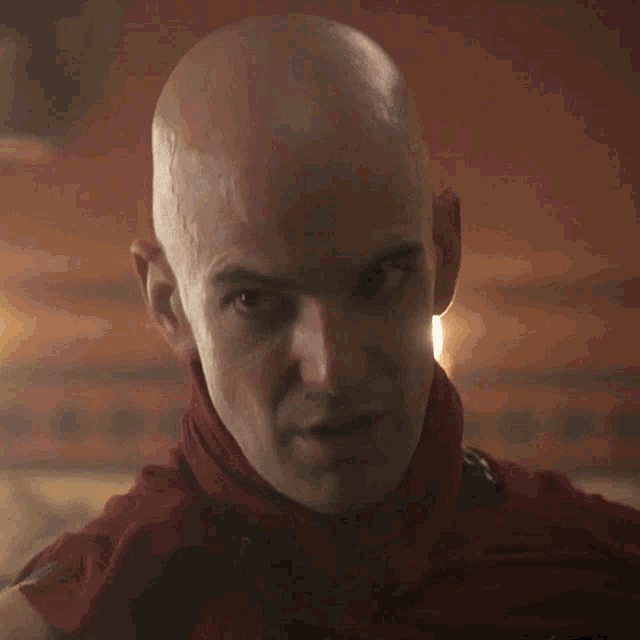 a bald man wearing a red scarf around his neck