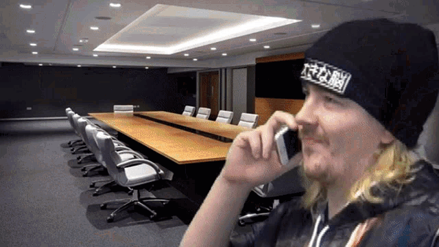 a man talking on a cell phone in a conference room with a long table