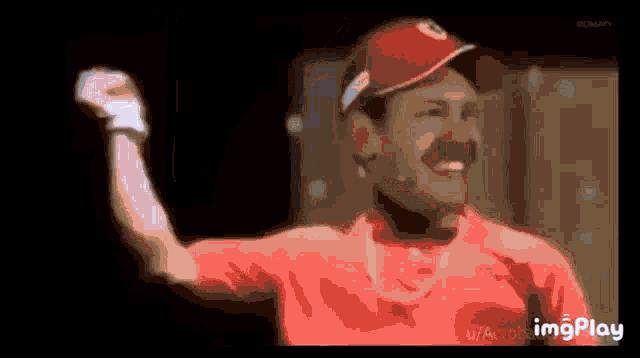 a man wearing a red hat and a red shirt holds his fist in the air .
