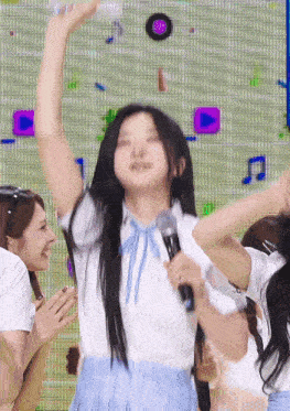 a girl in a blue skirt is holding a microphone in front of a screen with music notes .