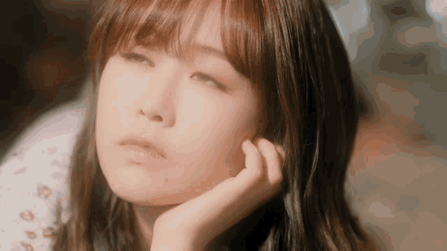 a close up of a woman with her hand on her chin