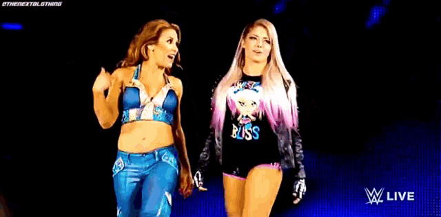 two female wrestlers are walking on a stage holding hands .