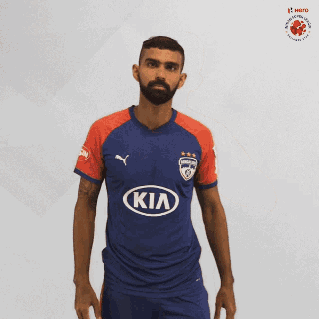 a man with a beard wearing a blue and red kia jersey