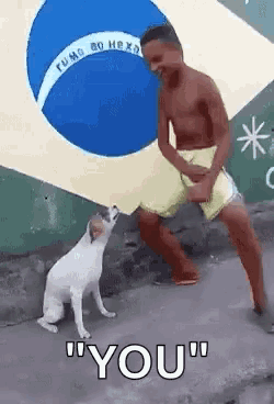 a shirtless man dancing with a dog in front of a brazilian flag .