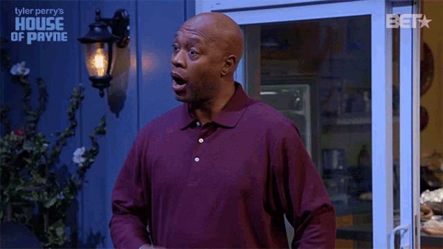 a man in a purple shirt is standing in front of a sign that says house of payne