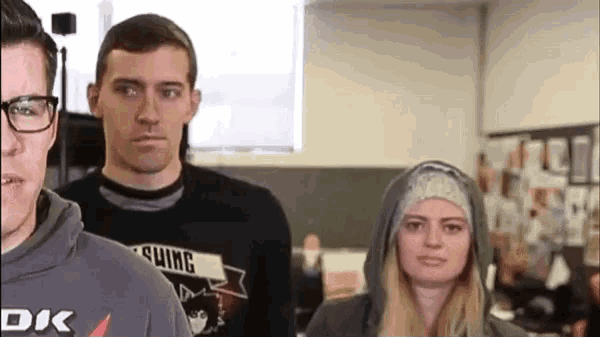 a man wearing a shirt that says shing is standing next to a woman wearing a hooded sweatshirt .