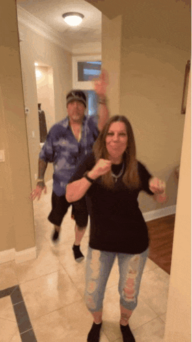 a man and woman are dancing in a hallway and the woman is pointing at the camera