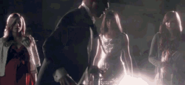 a man in a tuxedo and a woman in a white dress are standing next to each other in a dark room .