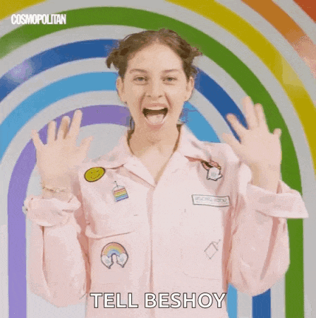 a woman in a pink shirt with a rainbow in the background is making a funny face .