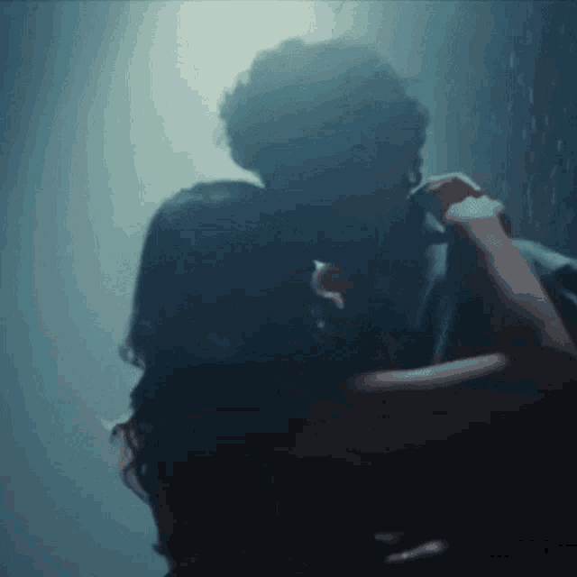 a man and a woman are kissing in the dark in a room .