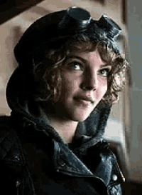 a woman wearing a hat and goggles is looking at the camera .