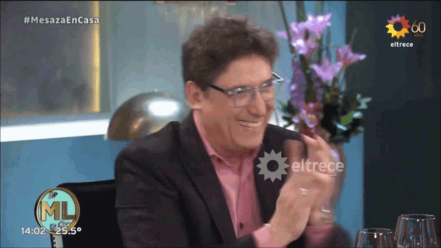 a man in a suit and pink shirt applauds on a television show called mesaza en casa