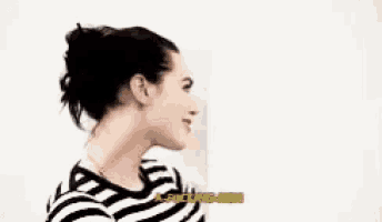 a woman in a striped shirt is smiling and talking to a man .