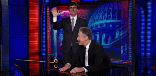 a man in a suit and tie is sitting at a table in front of a screen that says cnn on it