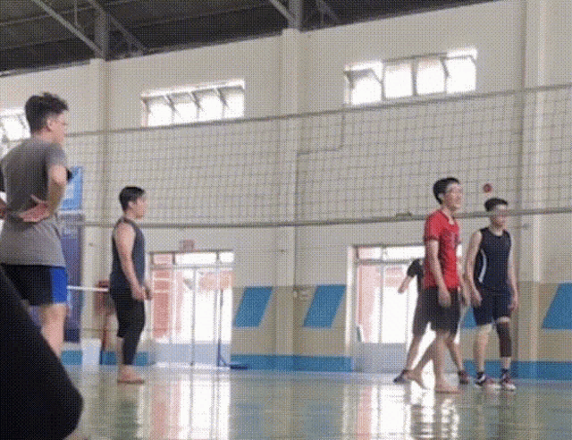 a group of people playing volleyball in a gym