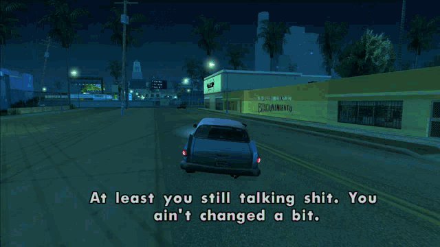 a car is driving down a street at night and says at least you still talking shit