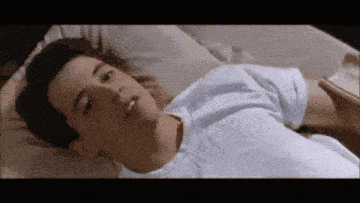 a man in a white shirt is laying in bed