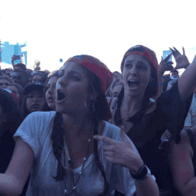a woman wearing a red hat is pointing at something in a crowd