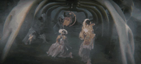 a group of people standing in a dark room with a skeleton in the background