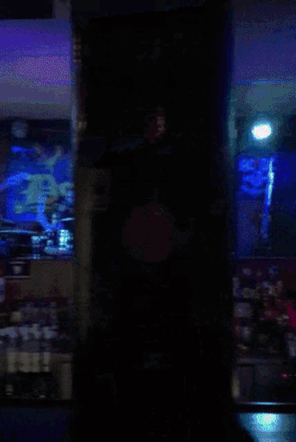 a man playing a guitar in a dark room with a green light behind him with the letter d on it