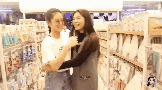 two women are hugging each other in a store while standing next to each other .