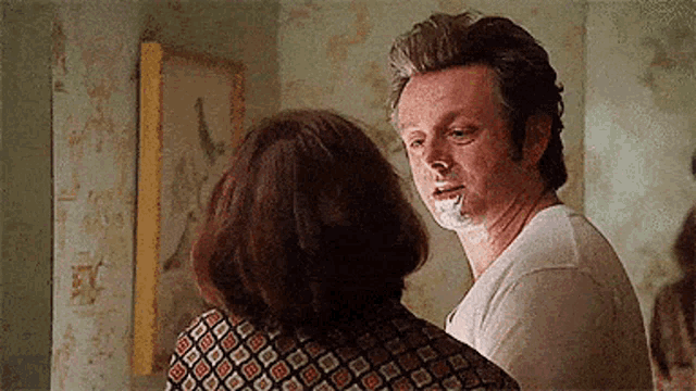 a man with a cigarette in his mouth is standing next to a woman in a room .