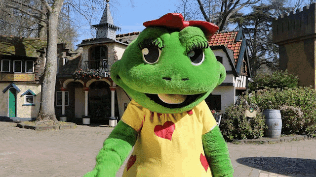 a frog mascot wearing a yellow and red shirt with hearts on it
