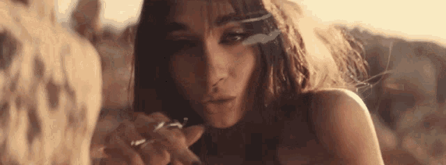 a woman is smoking a cigarette in the desert