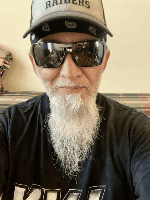 a man with a beard wears a raiders hat