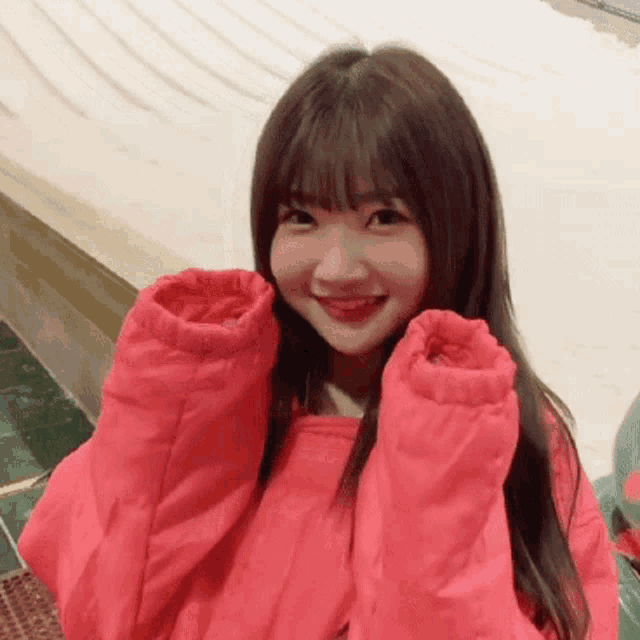 a girl in a pink jacket is smiling and holding her hands up