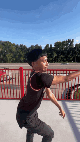 a young man stands in front of a red railing