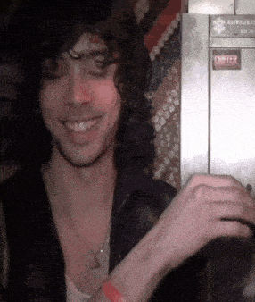 a man is smiling in front of a refrigerator that has a sticker on it that says ' do not open '