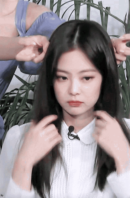 a woman in a white shirt is getting her hair done by another woman .
