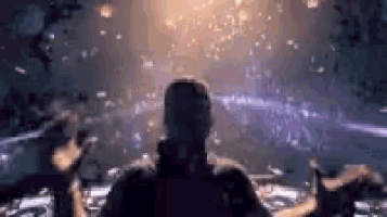 a man is standing in front of a crowd of people in a dark room watching fireworks .