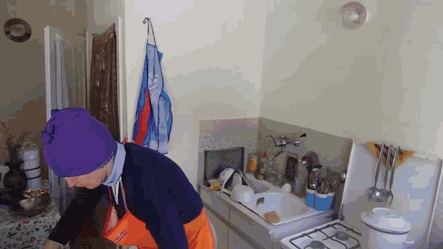 a woman wearing a purple hat and an apron that says ' coca cola ' on it is standing in a kitchen