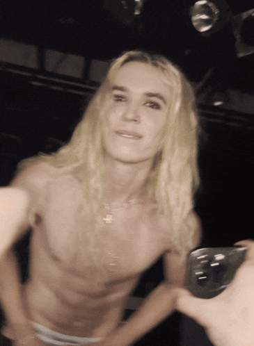 a man with long blonde hair taking a selfie