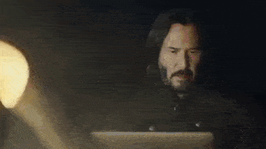 a man with a beard is using a laptop computer in a dark room .